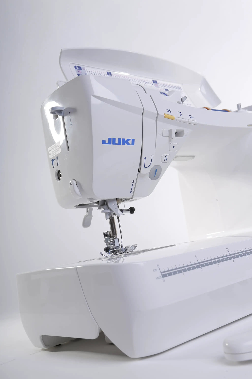 Juki HZL-DX7 computerized sewing machine, white with blue branding, side view.