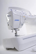 Juki HZL-DX7 computerized sewing machine, white with blue branding, side view.