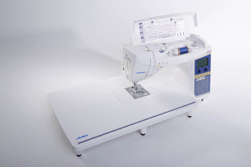 Juki HZL-DX7 computerized sewing machine on white extension table with blue control panel.