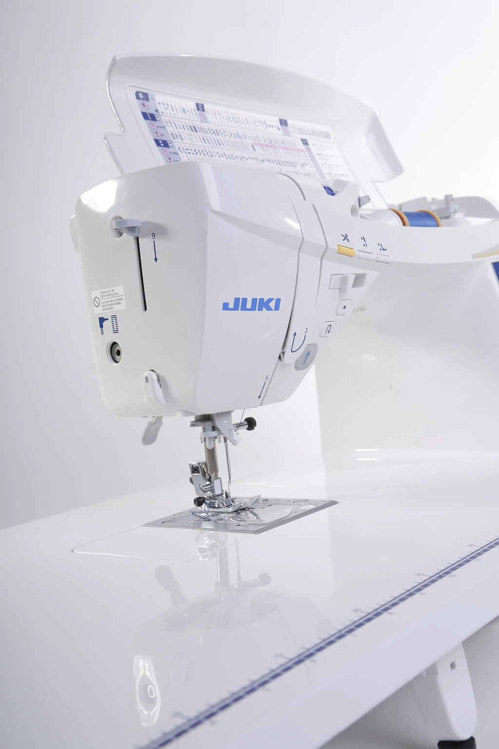 Juki HZL-DX7 computerized sewing machine, white with blue Juki logo on a white table.
