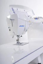 Juki HZL-DX7 computerized sewing machine, white with blue Juki logo on a white table.