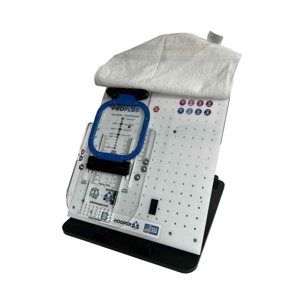 Hooper One hooping station with blue Pro Plus leveler hoop on perforated white base; towel on top