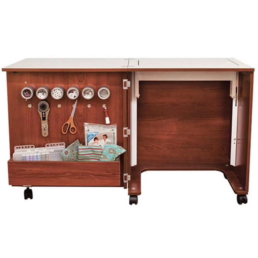 Sewing cabinet Inspira Create in teak; left pegboard with spools and scissors, plus a lower storage drawer on wheels.