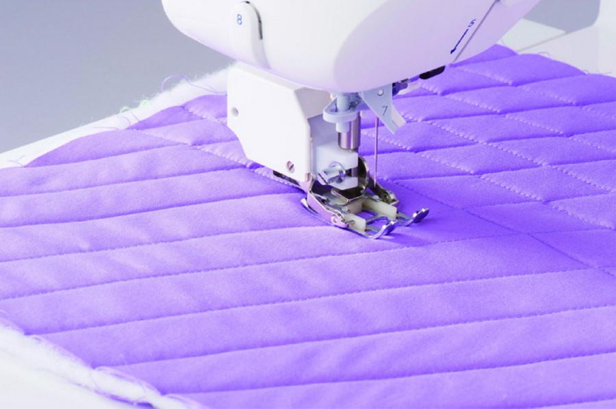 Sewing machine with Juki even feed walking foot stitching a purple quilted fabric