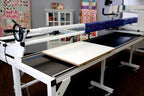 Handi Quilter Multi-Use Board Kit HQ quilting frame accessory on a white frame with fabric and sewing machine visible