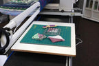 Multi-Use Board Kit by Handi Quilter on a green cutting mat with three fabric scraps and a purple-handled rotary cutter