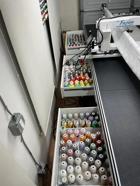HQ Secret Drawer Studio 2 quilting frame accessory by Handi Quilter, open drawers filled with colorful thread spools