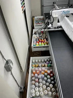 HQ My Secret Drawer by Handi Quilter, thread & yarn organizer with colorful spools in open drawers beside HQ Fusion