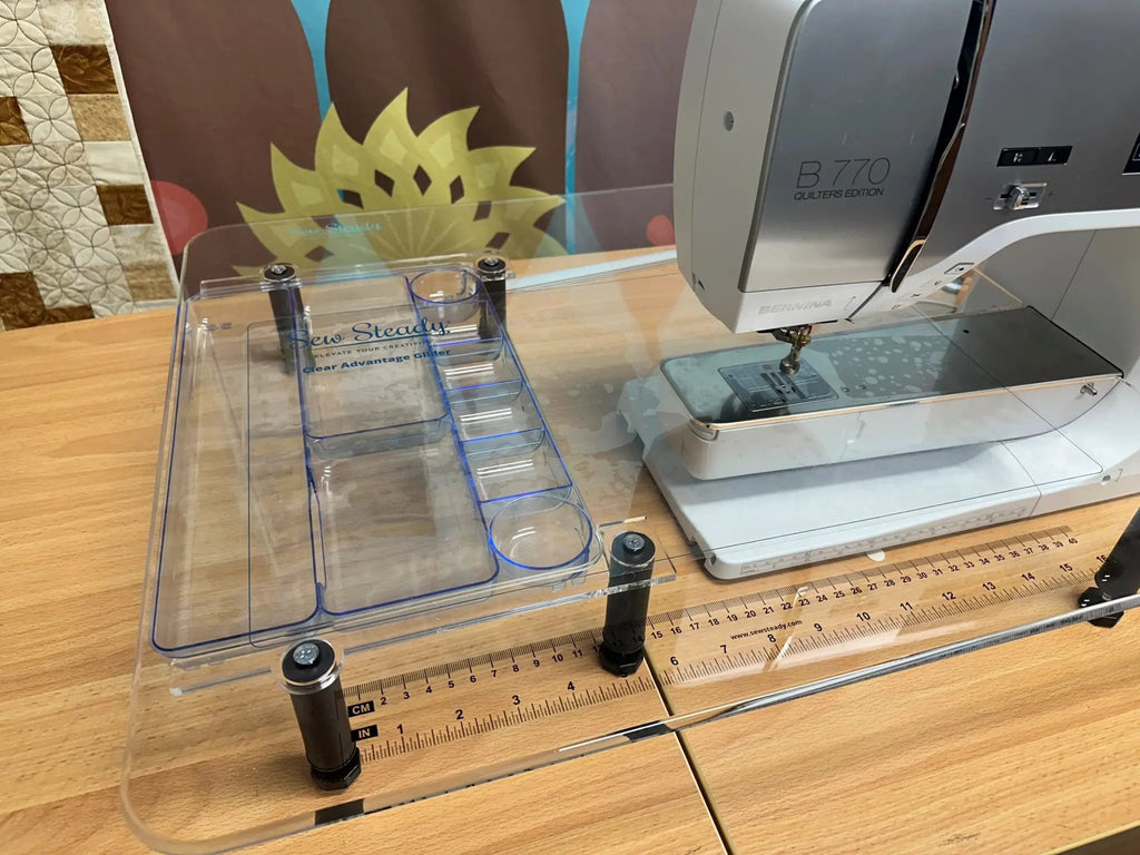 Sew Steady Clear Ruler Work Glider, clear acrylic grid ruler shown beside a Bernina B770 sewing machine.