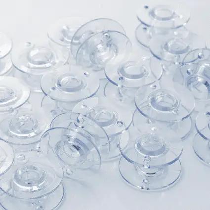 Clear plastic bobbins scattered on a light surface, multiple pieces
