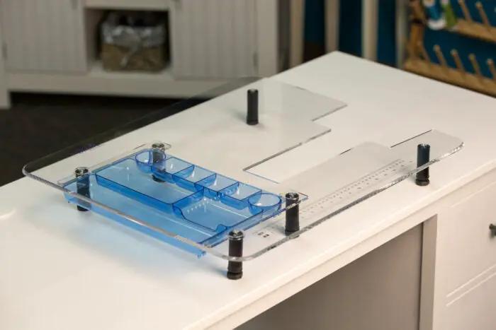 Handi Quilter extension table for HQ Stitch 710 machine; clear acrylic surface with blue accessory tray
