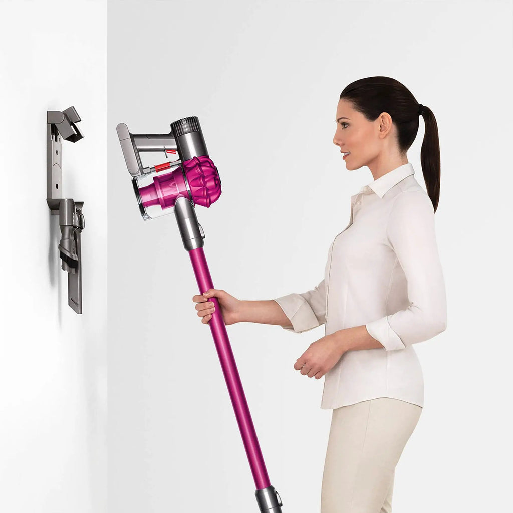 Dyson V6 Motorhead cordless stick vacuum, magenta, held by a woman.