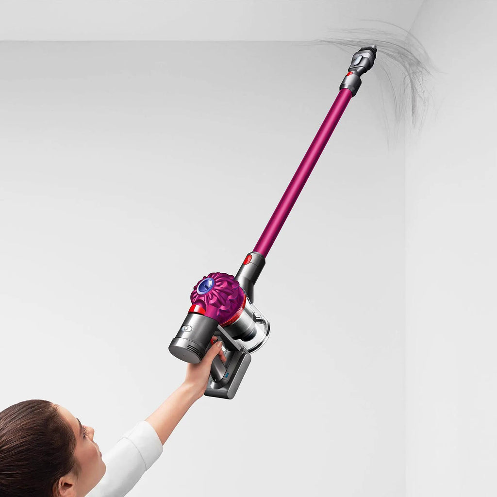 Dyson V7 Motorhead cordless vacuum with pink wand, held by a person.