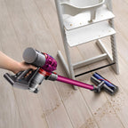 Dyson V7 Motorhead cordless vacuum on wood floor with purple body, cleaning scattered crumbs