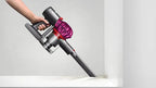 Dyson V7 Motorhead cordless vacuum with gray body and purple cyclone, handheld wand cleaning a shelf edge