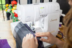 Baby Lock Serenity 4-Thread Serger sewing machine in white with hands guiding purple fabric.