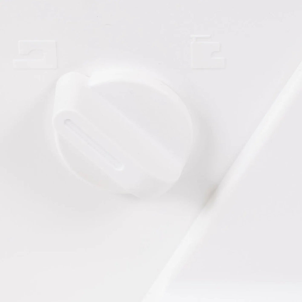 Sewing machine control knob; white plastic dial on a white surface.