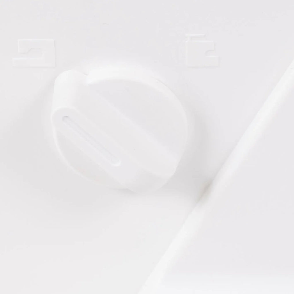 Sewing machine control knob; white plastic dial on a white surface.
