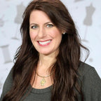 Touch of Lace workshop headshot; smiling woman with long dark hair, gray top, gold pendant.