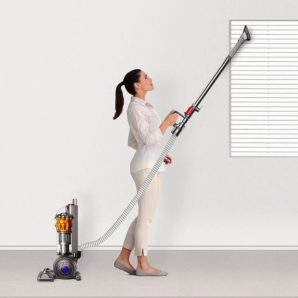 Dyson Small Ball Multifloor UP15MF vacuum with long wand and orange cyclone; woman in white using it