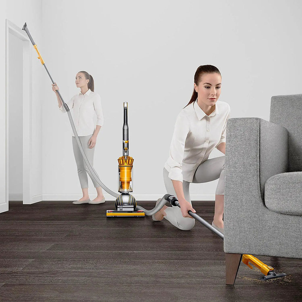 Dyson Ball Multifloor II vacuum with yellow accents, shown with two people cleaning different areas of a living room.