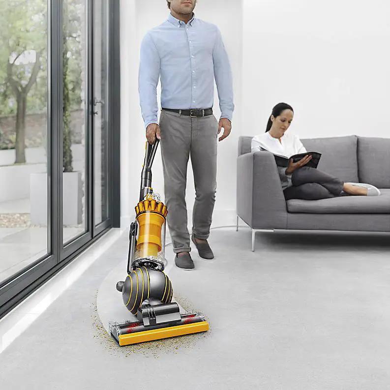 Dyson Ball Multifloor II vacuum cleaner, yellow and gray, being pushed across a living room floor.