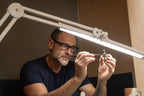 Daylight Lumi LED Task Lamp, white adjustable arms lighting a hobby miniature being assembled.