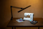 Lumi Task Lamp Satin Black Limited Edition; adjustable black metal desk lamp beside sewing machine.