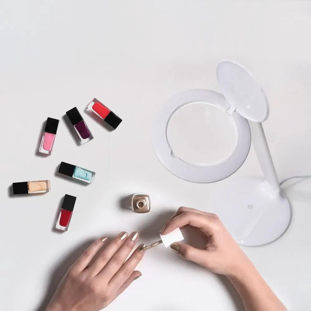 Daylight Halo LED Table Magnifier; white magnifying lamp beside assorted nail polish bottles