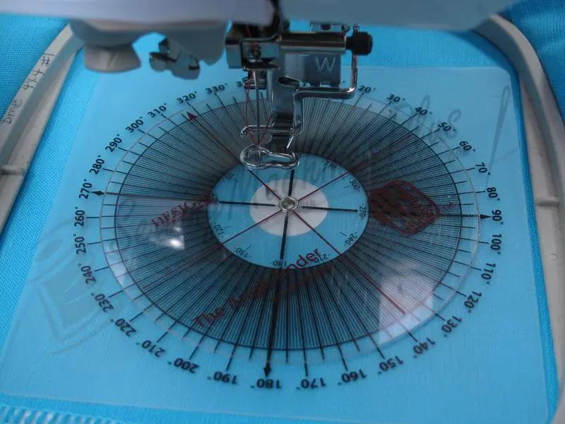 Machine embroidery tool set by DIME on a blue sewing machine surface, featuring a circular gauge and embroidery foot.