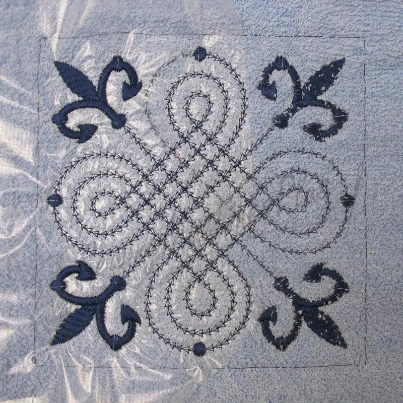 Machine embroidery design on light blue fabric with blue thread detail.