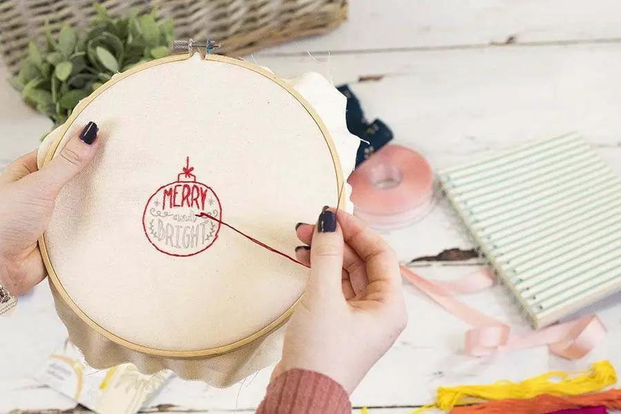 Threaders Embroidery Transfer Sheets Festive in use on fabric with a red Christmas ornament design in a hoop