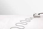 SEBO AIRBELT E3 Premium canister vacuum in Arctic White with grey accents, cord trailing on white surface.