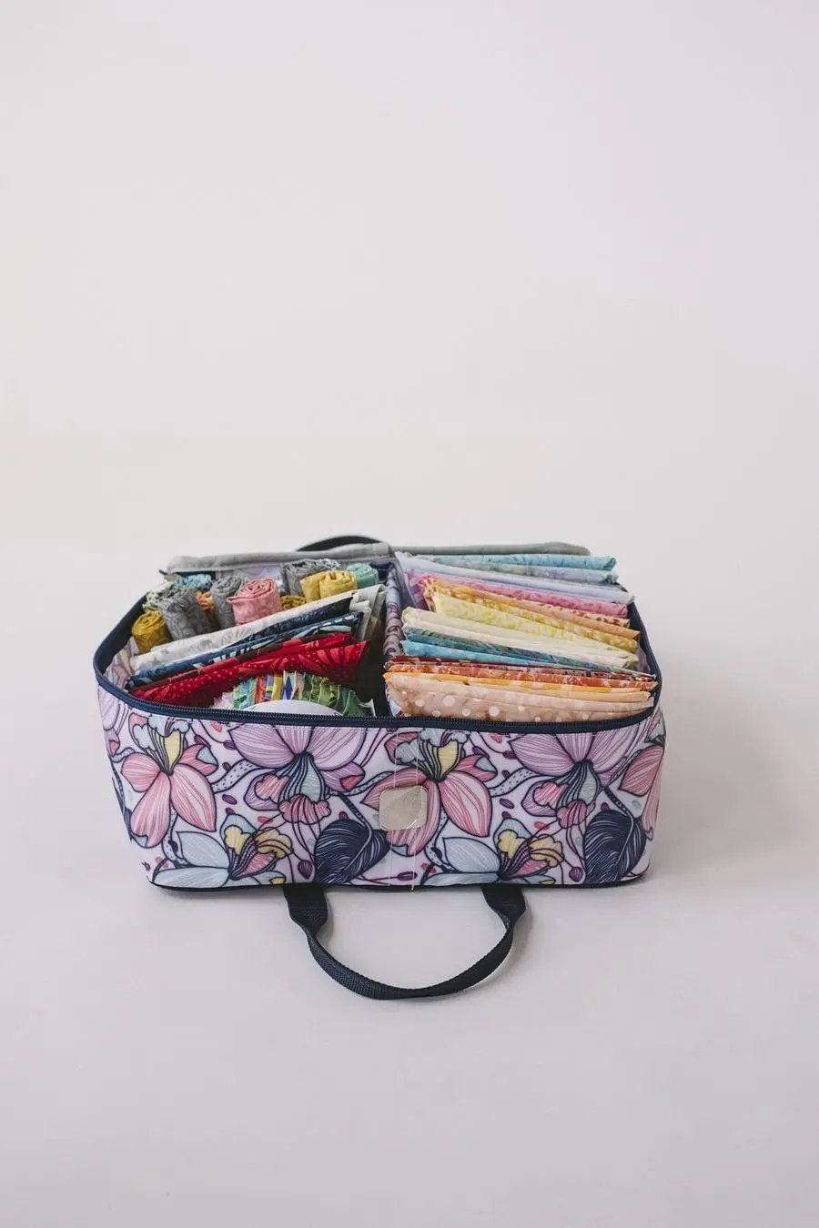Bluefig Quilter Deluxe Combo 19in wheeled bag with floral purple exterior and packed fabric bundles inside.