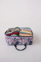 Bluefig Quilter Deluxe Combo 19in wheeled bag with floral purple exterior and packed fabric bundles inside.
