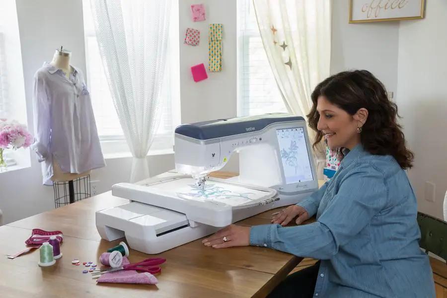 Brother Stellaire Innov-is XJ1 sewing and embroidery machine on table with white body and colorful thread spools nearby