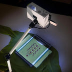 DIME Maximum View Projector on a white adjustable stand projecting onto green patterned fabric