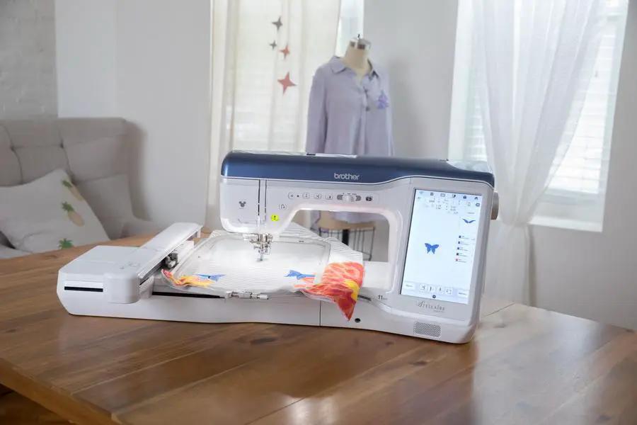 Brother Stellaire Innov-is XJ1 sewing and embroidery machine; white with blue top on a wooden table