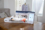 Brother Stellaire Innov-is XJ1 sewing and embroidery machine; white with blue top on a wooden table