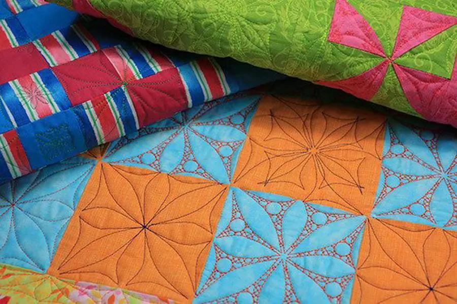 Quilt: DIME Windmill Garden Quilt, bright orange and blue windmill-block designs, stacked with a green quilt