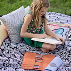 Bluefig University Learn to Sew Kit Lil Wrap Class 100 fabric kit; child sewing on a patterned quilt outdoors