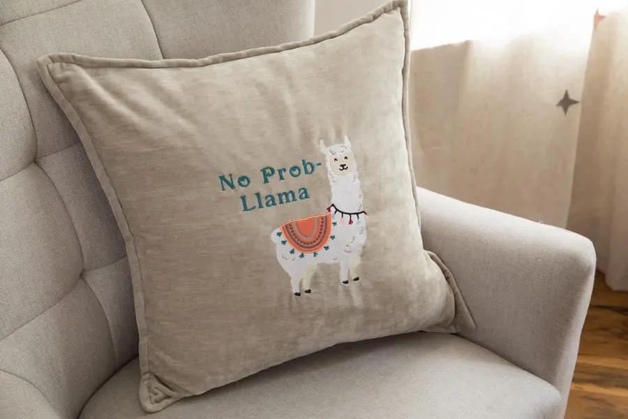 Throw pillow featuring llama embroidery and No Prob-Llama text on beige fabric.