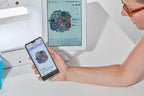 Brother Stellaire Innov-is XJ1 sewing and embroidery machine, white, with smartphone displaying embroidery design