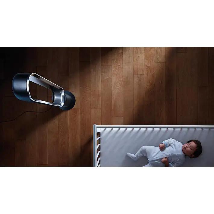 Dyson AM07 Black tower fan on wood floor beside a crib with a sleeping baby