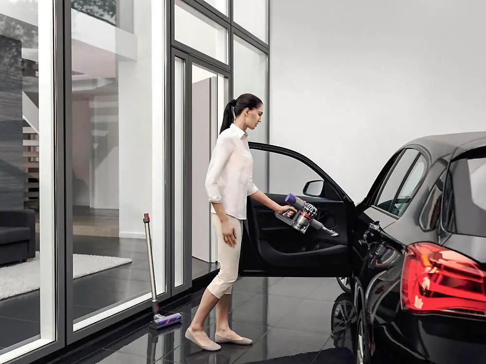Dyson V8 Animal cordless vacuum; bottom-release dust cup, two units shown cleaning a car interior.