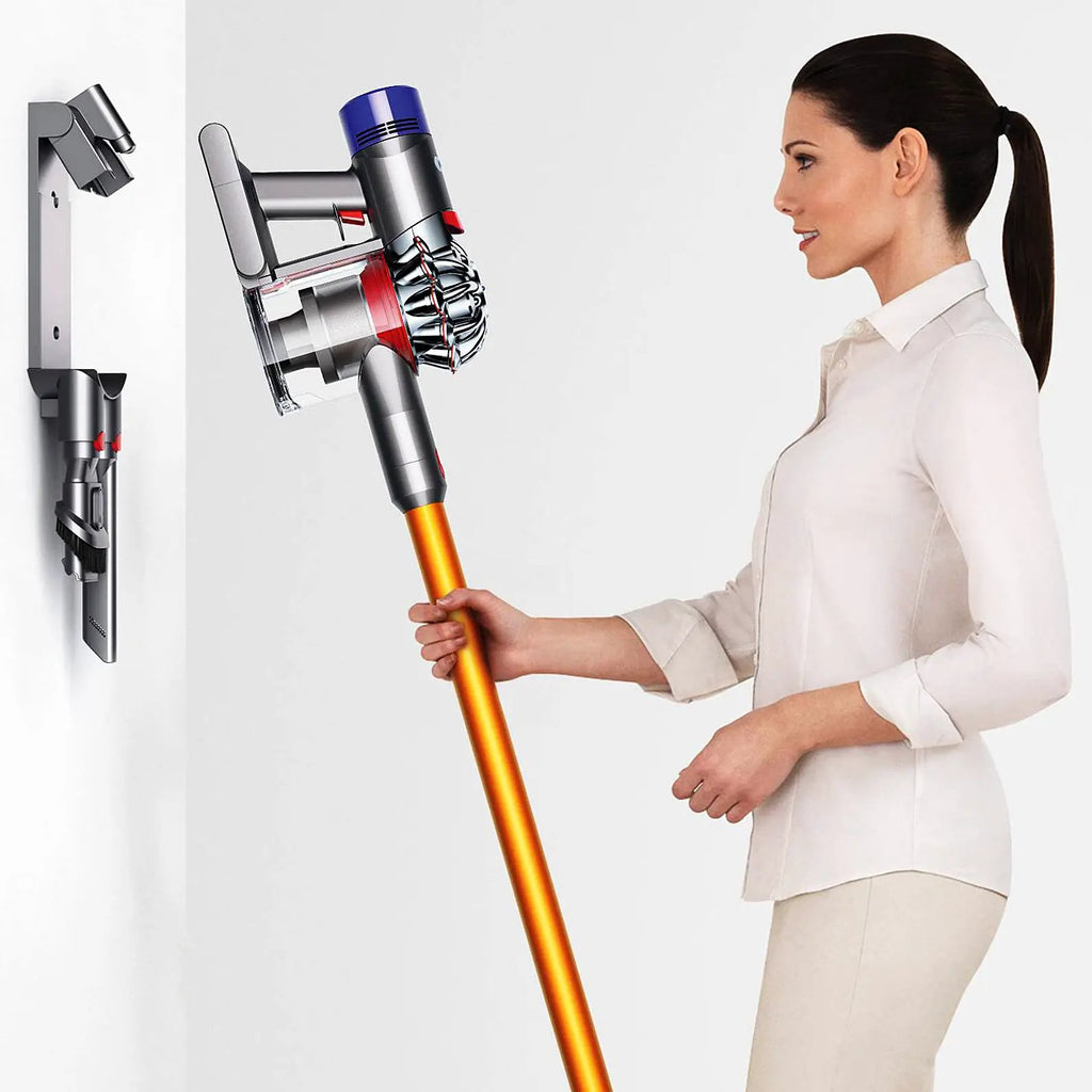 Dyson V8 Absolute vacuum cleaner with orange wand, silver body, transparent dust cup; wall dock with attachments
