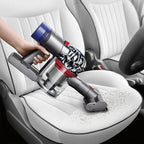 Dyson V8 Absolute handheld vacuum in gray with bottom-release dust cup on car seat.