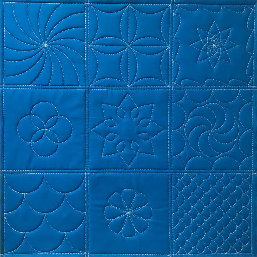 Ruler Work Kit from Sew Steady: blue quilt with 9 square blocks of various ruler-work quilting patterns