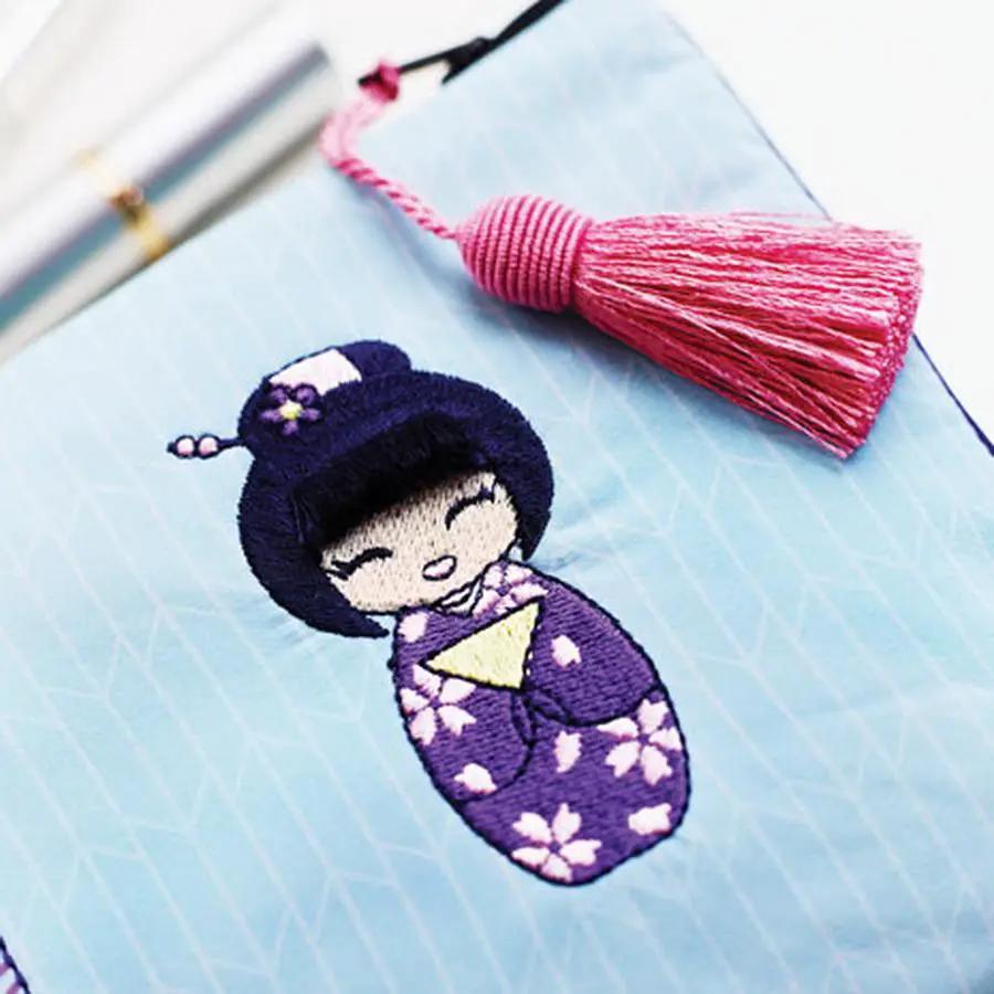 Sew Tech embroidery hoop 80mm x 80mm featuring blue fabric with a purple kokeshi embroidery and a pink tassel.