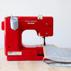 Janome Derby Line portable sewing machine, red bandana-blush color with spool of light blue thread